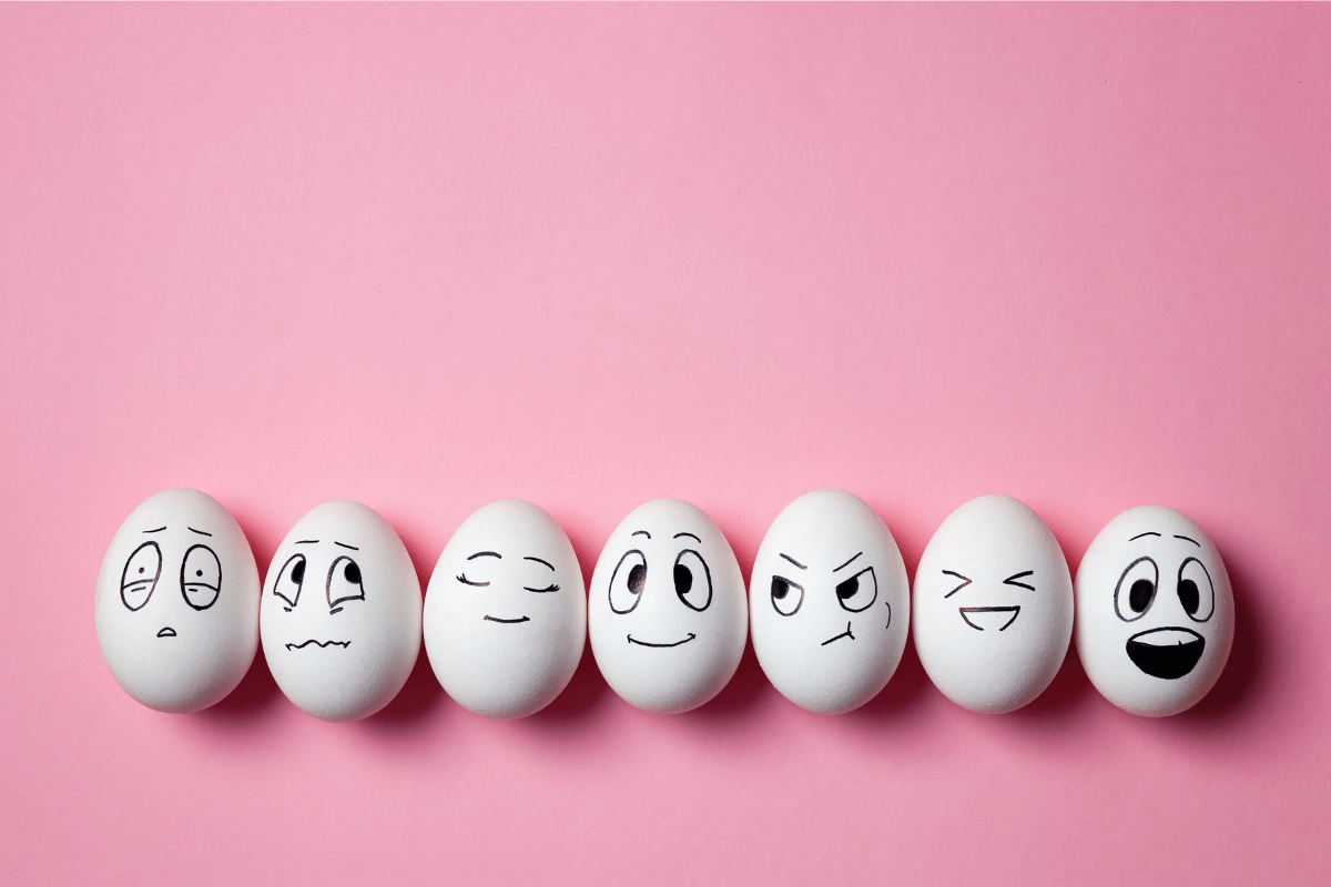 Une représentation créative d'œufs aux expressions faciales variées disposés sur un plateau, symbolisant la diversité.
